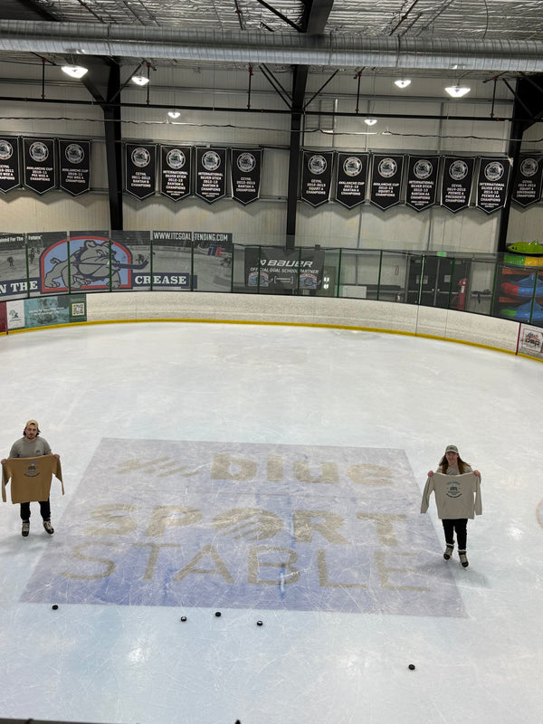 Co-founders Ryan (left) and Braden (right) pictured on the ice next to the Blue Sport Stable logo each holding a Heritage hoodie from Putt Snipe Celly. Thank you to Blue Sport Stable for hosting our photo shoot.