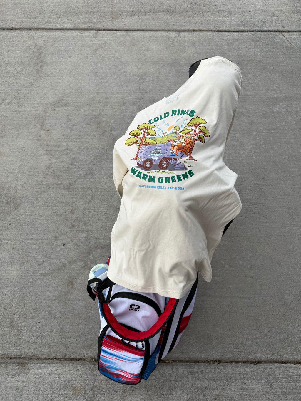 back view of long sleeve tee in the color heather natural draped over a golf bag featuring the full Fresh Sheet graphic from Putt Snipe Celly
