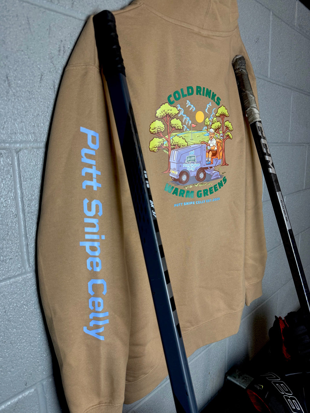Locker Room setting featuring the Fresh Sheet design in the Sandstone colored hoodie showing both the main back design and signature word mark on left sleeve from Putt Snipe Celly.