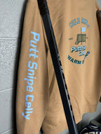 Locker Room setting featuring the Heritage design on a Sandstone colored hoodie showing both the main back design and signature word mark on left sleeve from Putt Snipe Celly.
